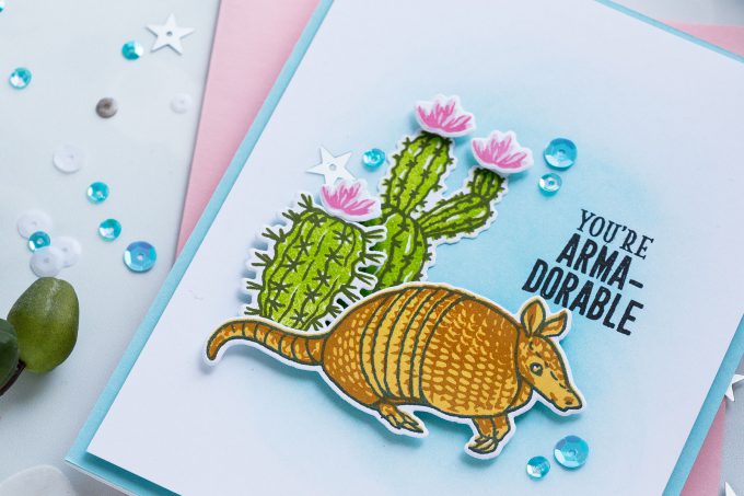 I used Soft Pool ink to blend a light blue background. Next, I foam mounted my armadillo stamped in Black, Butter Bar and Caramel and two cacti images stamped in Green Apple and Forever Green.